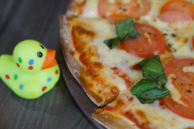 a small yellow rubber duck next to a pizza