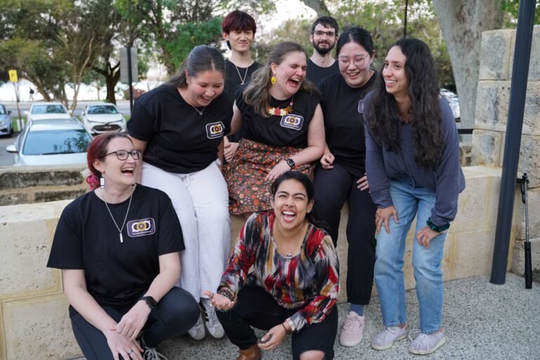 a group of people sitting and standing, laughing and smiling in a candid manner