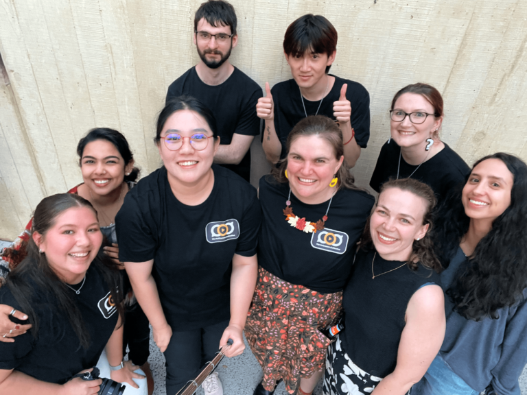 A group of people standing and smiling. The photo is taken from a high angle as someone is holding a selfie stick.