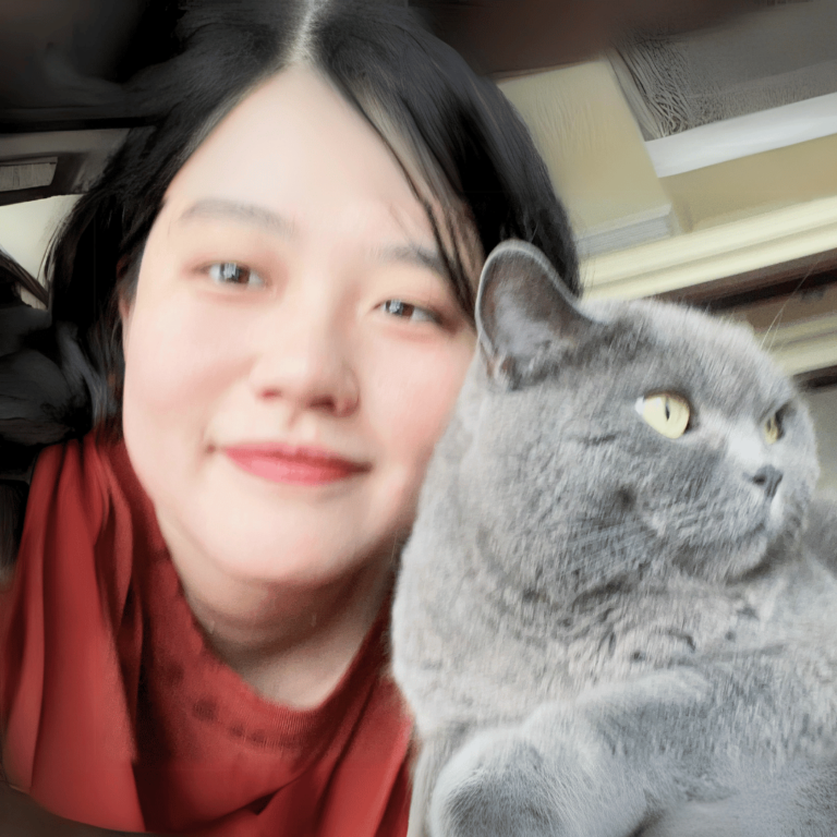 Chinese girl in a red shirt, with dark hair to her shoulders, cuddling a grey cat