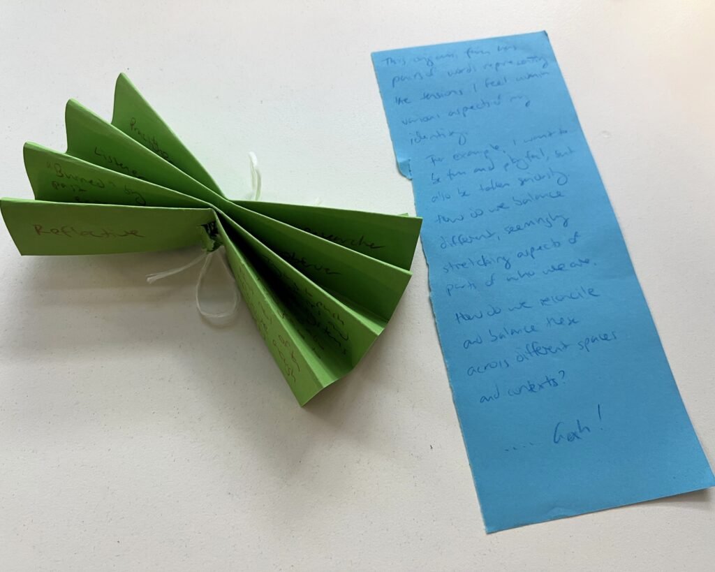 blue paper with writing describing the folded green origami 'fan' next to it