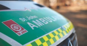 Front of a Western Australian ambulance: the bonnet is green and white with a yellow and green checkered strip above the fender. St John Ambulance and a red and white logo are visible.